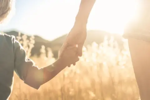 Un niño y un adulto se toman de la mano al atardecer. Pensamientos de orgullosa frases cortas para un hijo varon.