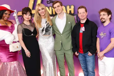 Hannah Montana obsada świętuje 20. rocznicę serialu. Gwiazdy w olśniewających strojach pozują na fioletowym dywanie.