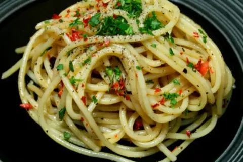 Pyszne spaghetti aglio e olio peperoncino, posypane natką pietruszki i pieprzem.