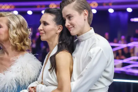 Katarzyna Zillmann i jej partnerka w białych strojach, czule objęte, na tle fioletowych świateł.