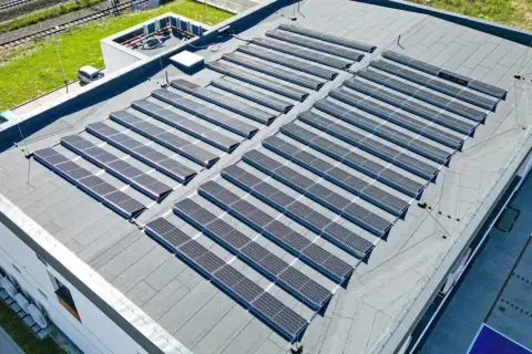Nowoczesny dom z płaskim dachem pokryty rzędami paneli słonecznych, które czerpią energię ze słońca.
