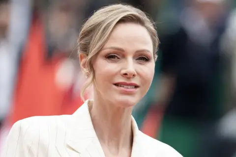 La princesa de Mónaco, Charlene Wittstock, sonríe con un traje blanco a rayas.