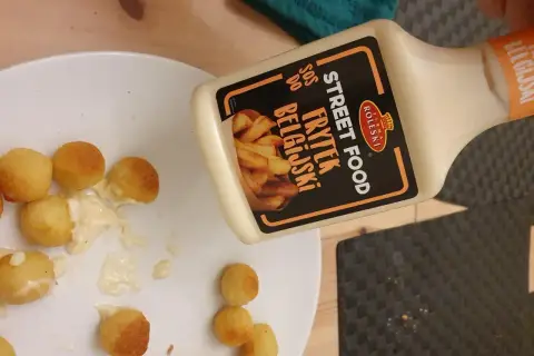 Kula frytek na talerzu, obok butelka sosu belgijskiego Street Food.