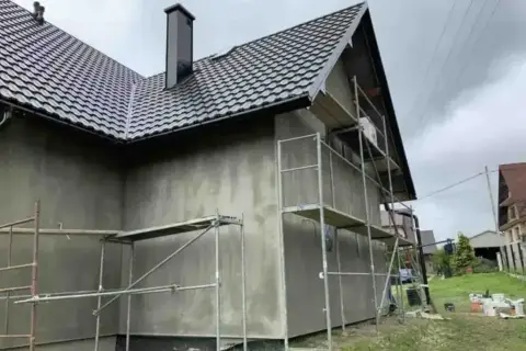 Dom w trakcie prac elewacyjnych, rusztowania wokół ścian. Zastanawiasz się, ile kosztuje elewacja domu?