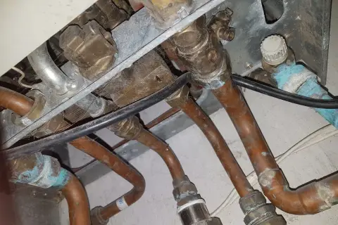 Instalacja pieca gazowego Vaillant z miedzianymi rurami. Widoczne przyłącza i zawory, być może problem ze słabym ciśnieniem ciepłej wody.