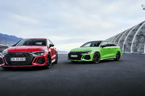 Dwa Audi RS 3 Sportback: czerwone i zielone, zaparkowane na zewnątrz.