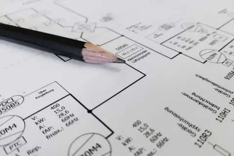 Ołówek na schemacie instalacji elektrycznej. Czy panele fotowoltaiczne trzeba zgłaszać? Dokumentacja techniczna zawiera dane urządzeń.