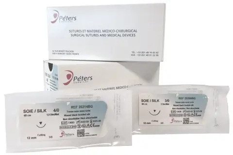 Opakowania z szwami chirurgicznymi Peters Surgical. Widać dwa pakiety z szwami jedwabnymi, w tym jeden z igłą tnącą.