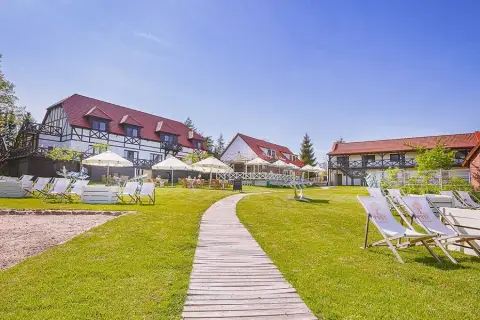 Słoneczny dzień na Mazurach. Urokliwe mazurskie miejscowości zapraszają do wypoczynku. Leżaki i parasole czekają na gości przy hotelu.