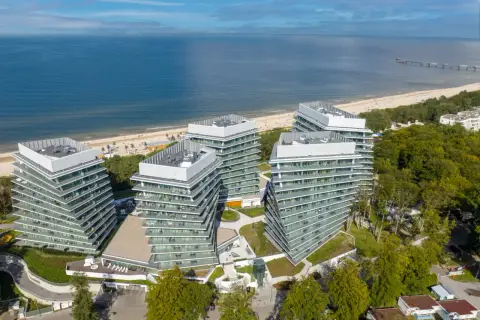 Nowoczesny wave resort z tarasami i widokiem na morze. Architektura idealnie wkomponowana w nadmorski krajobraz.