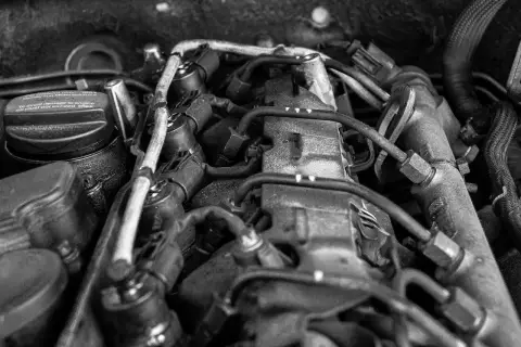 Widok silnika samochodowego. Na korku widać napis "To avoid damage to engine oil must not exceed max", sugerujący, że jest za dużo oleju w silniku.