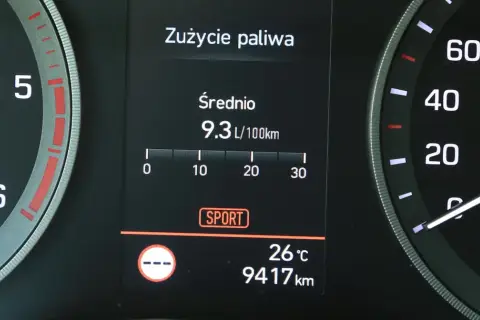 Na wyświetlaczu samochodu widać licznik spalania paliwa: średnie zużycie 9.3 L/100km. Obok widnieje tryb SPORT.