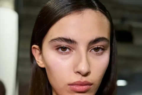 Primer plano de una joven con cejas pobladas y mirada intensa. Su piel luce natural y sus labios están ligeramente brillantes.