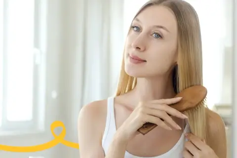 Kobieta szczotkuje włosy, przygotowując domowy peeling do skóry głowy.