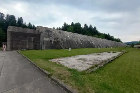 Ogromny betonowy bunkier w Frysztaku, otoczony zielenią i lasem.
