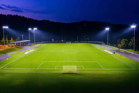 Piłkarskie boisko oświetlone mocnym oświetleniem stadionowym, gotowe na nocny mecz.