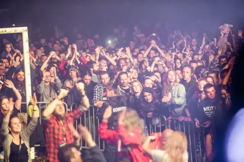 Tłum ludzi na festiwalu w Bieszczadach, z rękami w górze, cieszący się muzyką.