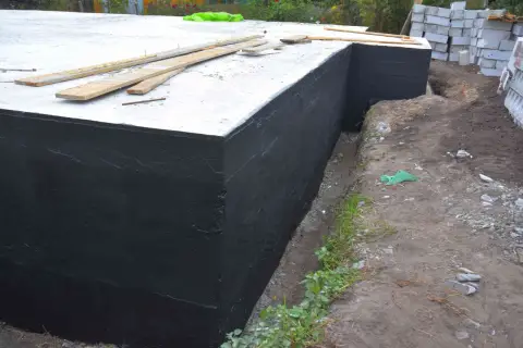 Zakończono hydroizolację piwnicy od zewnątrz. Czarna masa chroni fundamenty przed wilgocią.
