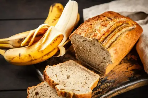 Pyszne, wilgotne ciasto bananowe, które zawsze się udaje. Obok leżą dojrzałe banany, gotowe do pieczenia.