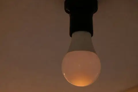 Żarówka LED, mimo że wyłączona, delikatnie żarzy się, budząc pytanie: dlaczego żarówka świeci po wyłączeniu?