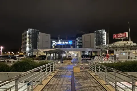 Nocny widok na hotel Radisson Blu Hamburg. Widać logo hotelu, znak Turkish Airlines i wejście.