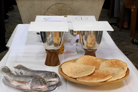 Dwa ryby i płaskie chleby na stole, symbolizujące rozmnożenie chleba i ryb.