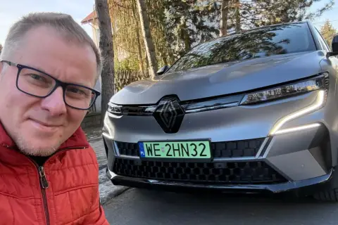 Mężczyzna w czerwonej kurtce robi selfie z nowym Renault Megane E-Tech.