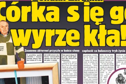 Bohdan Łazuka w swetrze w kratę, z pomarańczowym kubkiem.