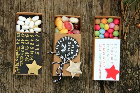 Kleine Schachteln zum Adventskalender to go basteln, gefüllt mit Süßigkeiten und nummerierten Tagen.