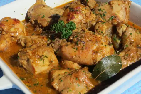 Delicioso conejo guisado en salsa dorada, con perejil picado y una hoja de laurel.