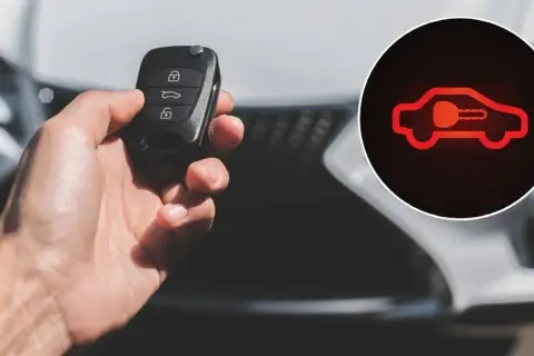 Dłoń trzyma kluczyk samochodowy. Obok widoczna czerwona kontrolka samochód z kłódką, sygnalizująca problem z immobilizerem.