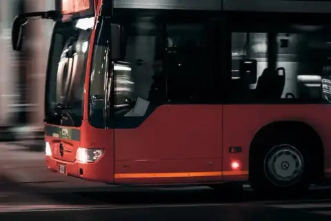 Czerwony autobus miejski w ruchu. Zastanawiasz się nad prawem jazdy kat D cena?