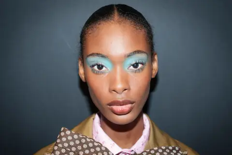 Ein auffälliges Silvester Make-up Look mit leuchtend türkisfarbenem Lidschatten und glänzenden Lippen.