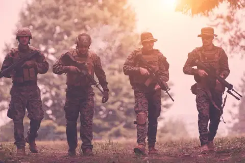 Czterech żołnierzy w kamuflażu, z karabinami, idzie przez las. Czy to przygotowanie do "Escape from Tarkov wymagania"?