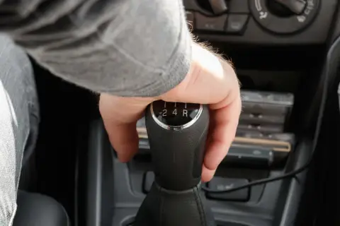 Mano cambiando de marcha en un coche, se escucha un ruido al girar el volante en movimiento a la derecha.