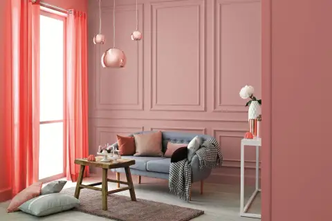 Przytulne, ciepłe wnętrza aranżacje w odcieniach różu i koralu. Sofa, stolik, poduszki i zasłony tworzą przytulną atmosferę.