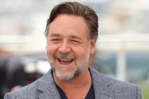 Uśmiechnięty Russell Crowe w szarym garniturze. Zastanawiasz się, ile lat ma Russell Crowe?
