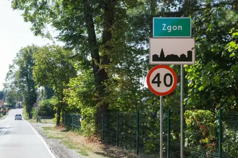 Zielony znak miejscowości Zgoń, obok znak z sylwetką miasta i ograniczenie prędkości do 40 km/h.