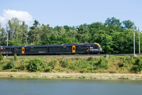 Czarny pociąg Leo Express jedzie wzdłuż zielonego brzegu. Zastanawiasz się, ile kosztuje bilet z Warszawy do Krakowa?