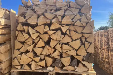 Un grand stère de bois, bien empilé et emballé sous plastique, prêt pour l'hiver.