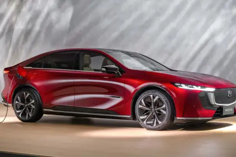 Czerwona Mazda 6e, ładowana elektrycznie, prezentuje nowoczesny design z eleganckimi liniami i dynamicznym profilem.