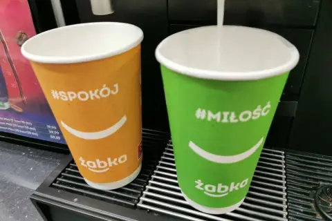 Dwie kawy z Żabki: pomarańczowa z napisem #Spokój i zielona z #Miłość. Duża kawa z Żabki ma 300 ml.