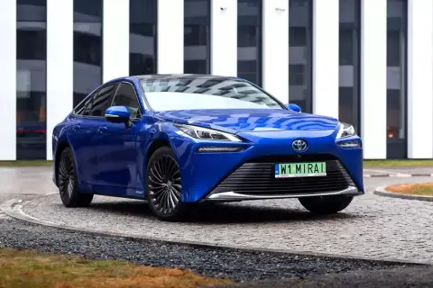 Niebieski samochód na wodór, Toyota Mirai, parkuje przed nowoczesnym budynkiem.
