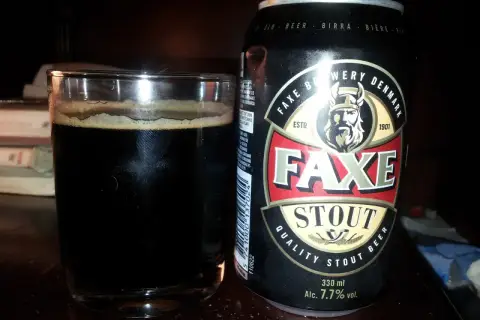 Szklanka ciemnego piwa obok puszki piwa Faxe Stout. Idealne na wieczór z dobrą książką.