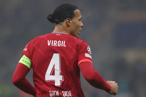 Piłkarz Liverpoolu Virgil van Dijk z numerem 4 na czerwonej koszulce. Na rękawie opaska "No to racism. Respect".