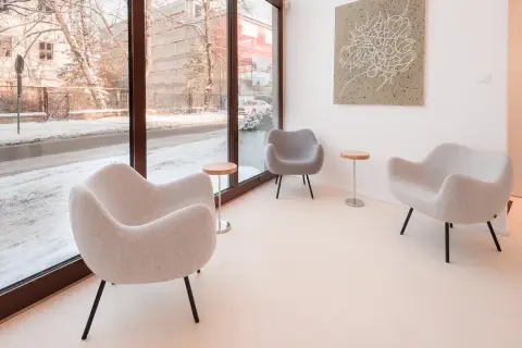 Nowoczesne fotele i stoliki tworzą przytulną przestrzeń, idealną do nauki podczas kursu fotografii wnętrz. Za oknem zimowy krajobraz.
