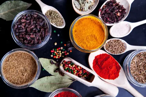 Kolorowe przyprawy, w tym kurkuma, papryka i kmin rzymski, ułożone na czarnym tle. Idealne do przygotowania aromatycznego garam masala przepis.
