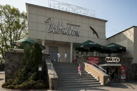 Budynek z napisem "Albatros" i sylwetką ptaka. Na schodach widać siedem dziewcząt z albatrosa, bawiących się w upalny dzień.
