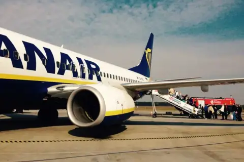Ryanair samolot na płycie lotniska, pasażerowie wsiadają po schodkach. Tanie loty z Łodzi czekają!