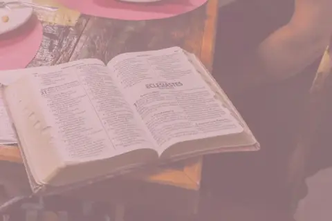 Otwarta księga z tekstem biblijnym, obok notatki ręczne. Wszystko to przypomina o marności nad marnościami, przemijaniu.